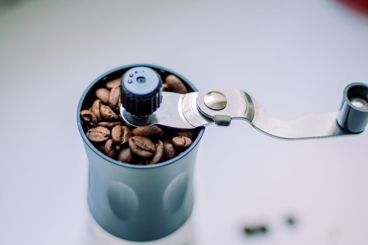Close-up of a manual coffee grinder filled with coffee beans.